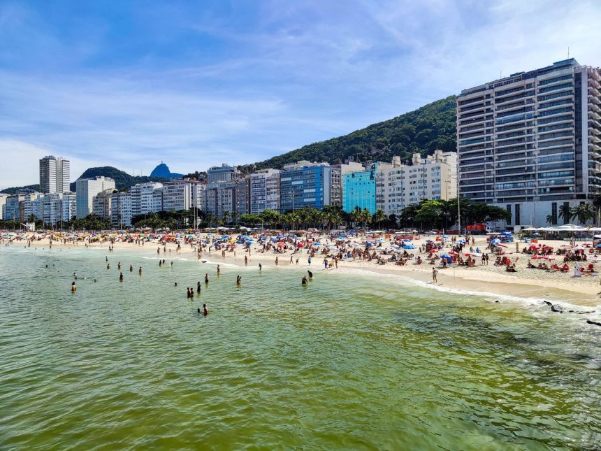 Praia de Copacabana, no Rio de Janeiro, com grande número de pessoas aproveitando um dia ensolarado