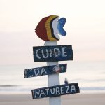 Placa colorida sobre preservação da natureza em uma praia de Guaratuba ao nascer do sol.