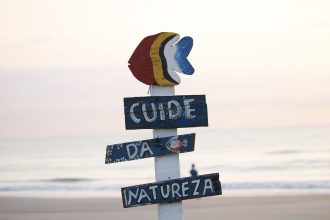 Placa colorida sobre preservação da natureza em uma praia de Guaratuba ao nascer do sol.