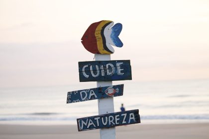 Placa colorida sobre preservação da natureza em uma praia de Guaratuba ao nascer do sol.