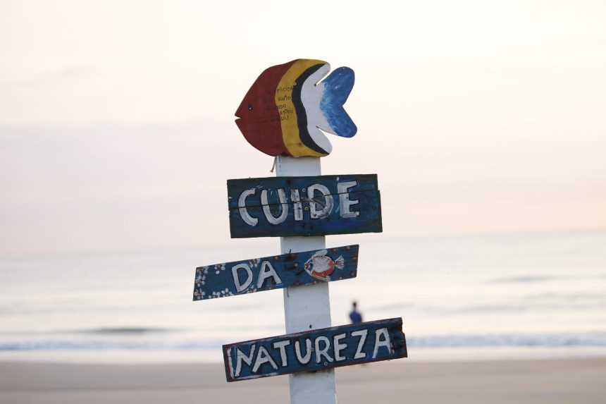 Placa colorida sobre preservação da natureza em uma praia de Guaratuba ao nascer do sol.