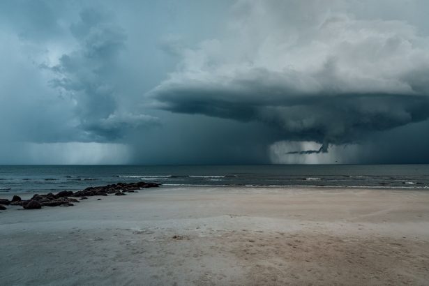 Praia arenosa com ondas agitadas e nuvens carregadas indicando a aproximação de uma tempestade.